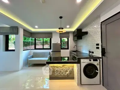 Modern kitchen with sleek design, featuring washing machine and stylish lighting.