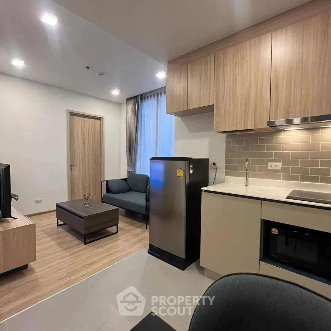 Modern living room with open kitchen, featuring sleek appliances and stylish wooden cabinetry.