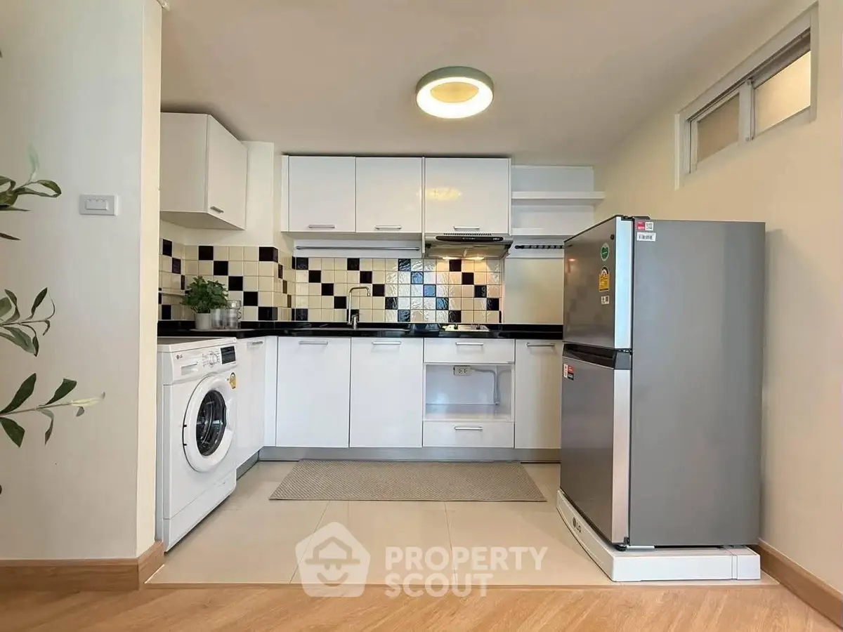 Modern kitchen with sleek appliances and stylish backsplash in cozy apartment.
