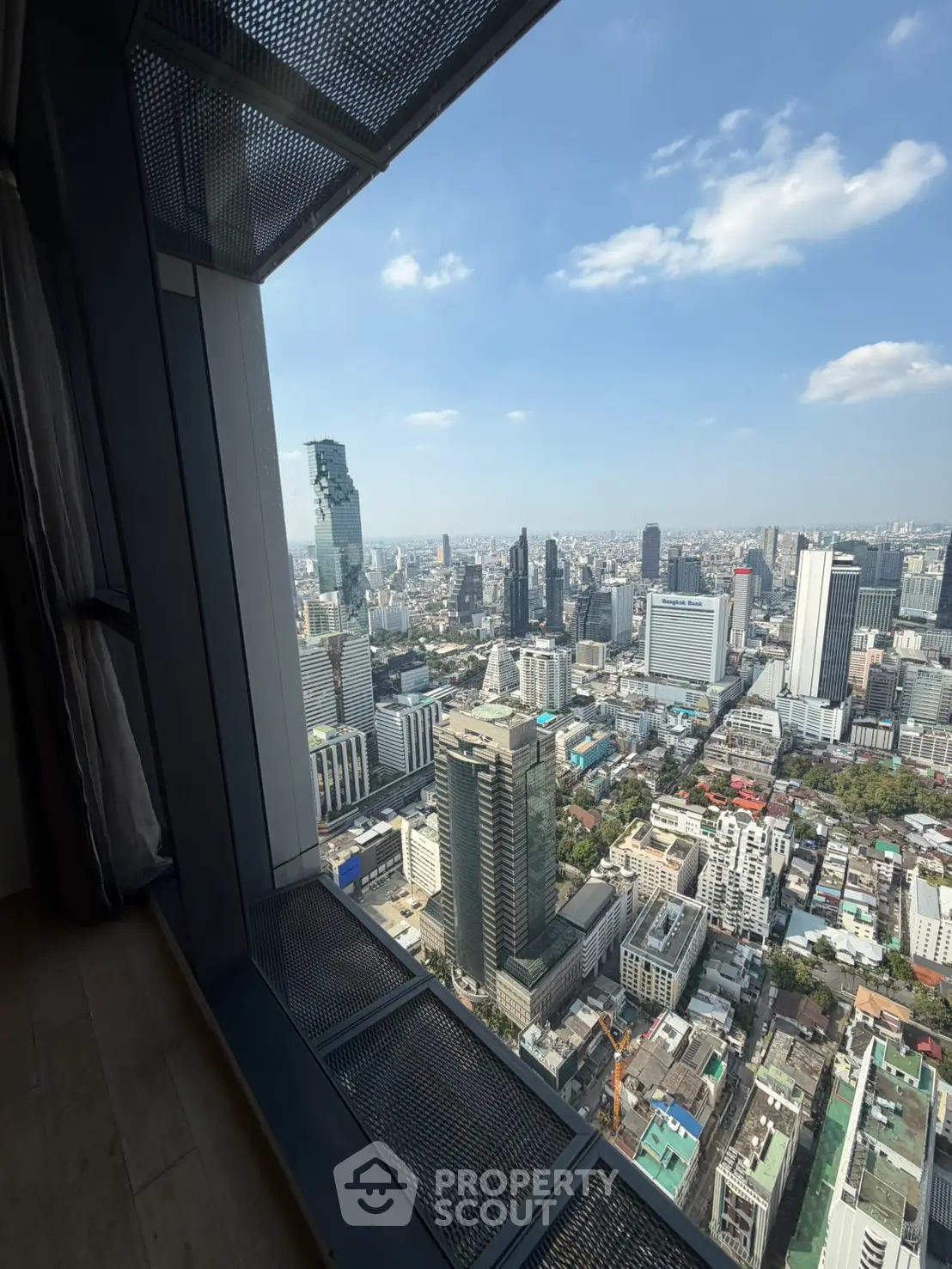 Stunning cityscape view from high-rise building window, showcasing urban skyline and clear blue sky.