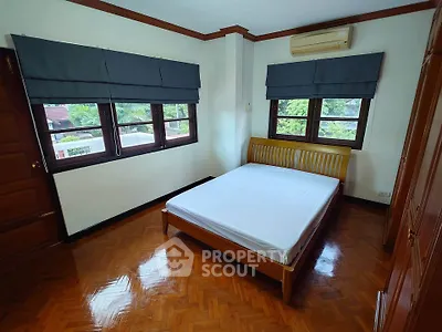 Spacious bedroom with wooden flooring and large windows for natural light.