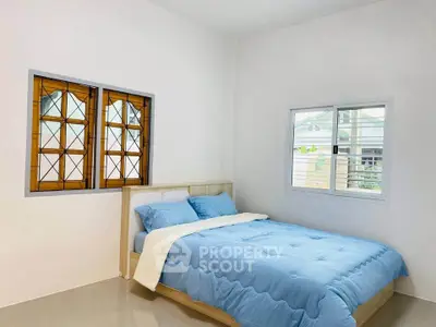Cozy bedroom with blue bedding and stained glass window in modern home.