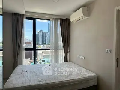Modern bedroom with large window and city view, featuring air conditioning and natural light.