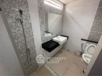 Modern bathroom with sleek fixtures and tiled walls, featuring a shower and toilet.