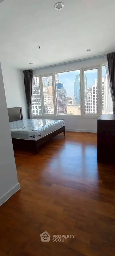 Spacious bedroom with city view and wooden flooring in modern apartment