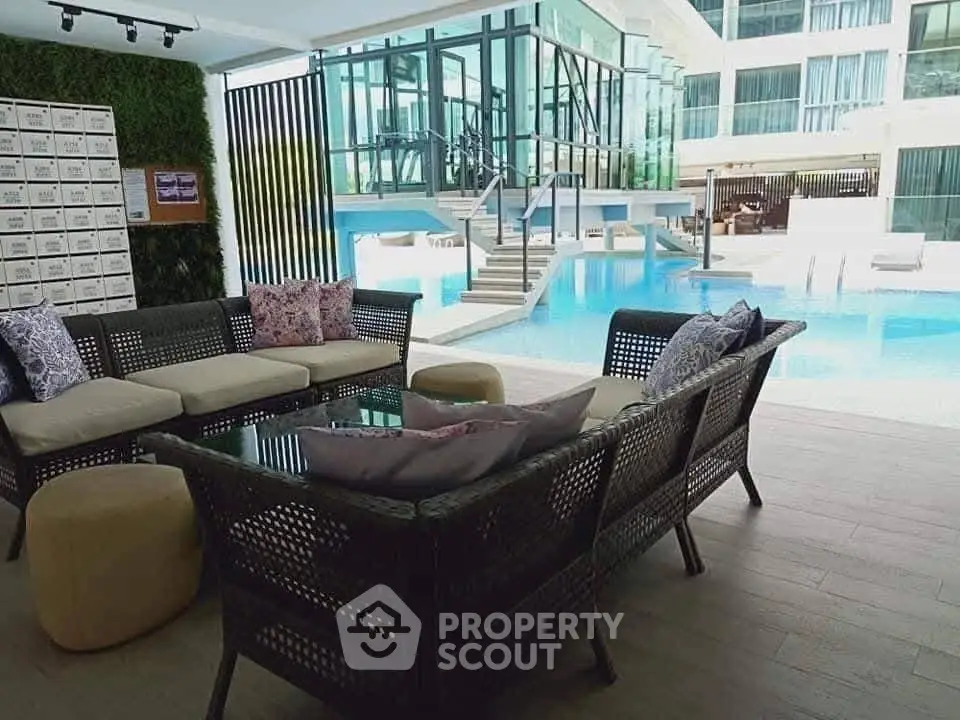 Luxurious poolside lounge area with modern seating and stunning pool view in upscale residential complex.