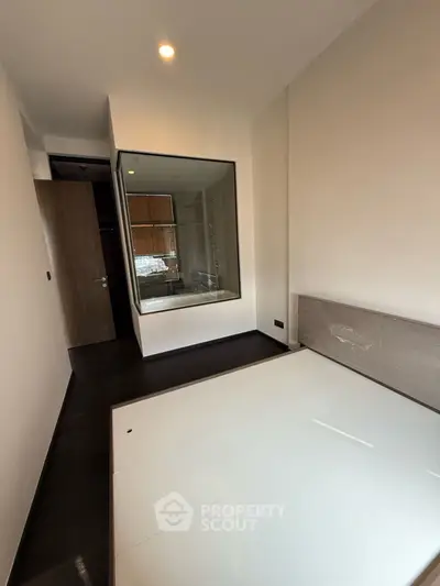 Modern bedroom with glass wall and dark wood flooring