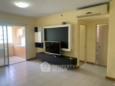 Spacious living room with modern TV setup and open kitchen view