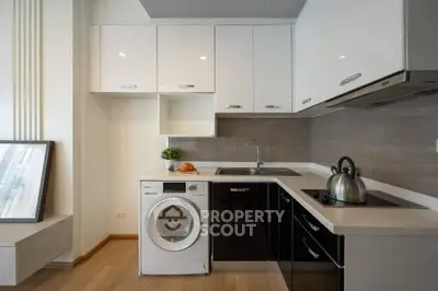 Modern kitchen with sleek cabinets and built-in appliances, featuring a washing machine and electric stove.