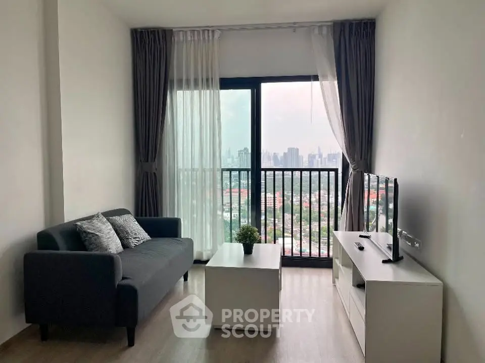 Modern living room with city view, stylish sofa, and sleek TV setup in a high-rise apartment.