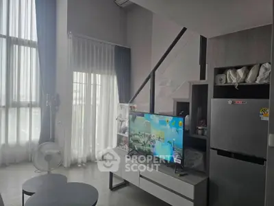 Modern living room with high ceilings and large windows, featuring a stylish TV setup and contemporary decor.