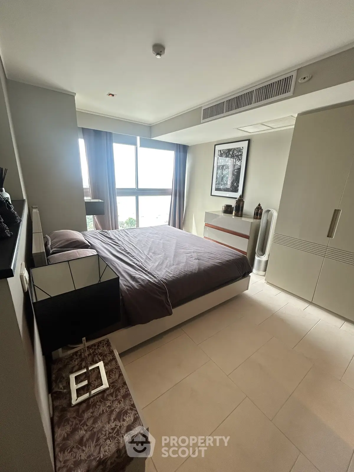 Modern bedroom with large window and stylish decor in a high-rise apartment.