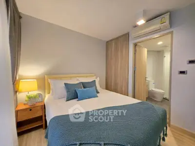 Cozy bedroom with modern decor and en-suite bathroom, featuring a comfortable bed and stylish lighting.
