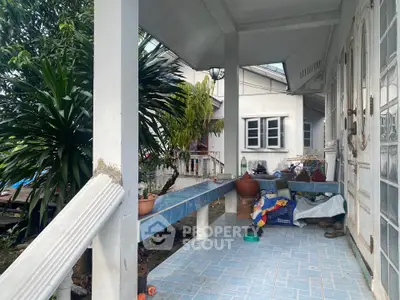 Charming porch with tiled flooring and lush greenery, perfect for relaxing outdoors.