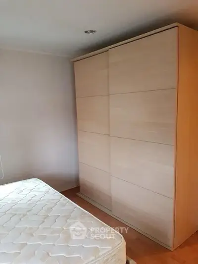 Minimalist bedroom with wooden wardrobe and mattress, ideal for cozy living.