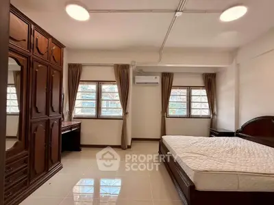 Spacious bedroom with elegant wooden furniture and large windows for natural light.