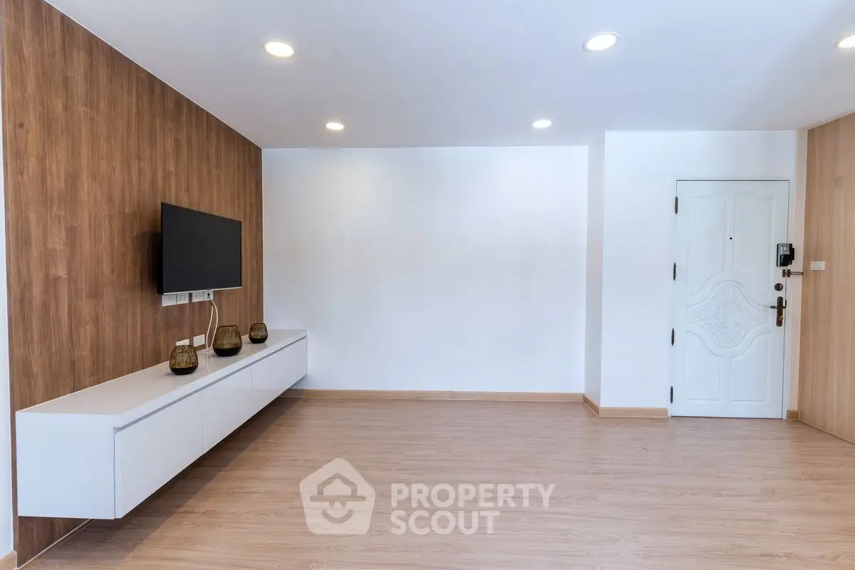 Modern minimalist living room with wooden flooring and wall-mounted TV