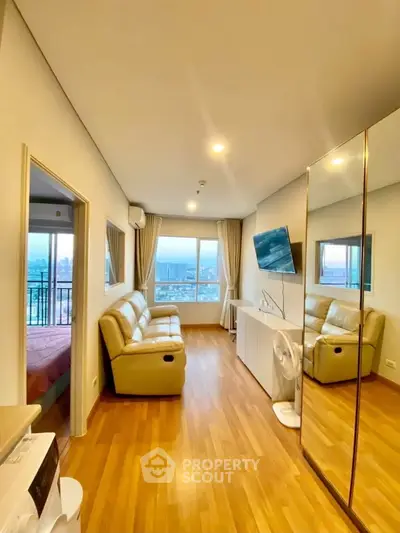 Modern living room with city view, featuring sleek furniture and wooden flooring in a high-rise apartment.