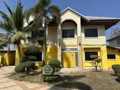 Charming yellow two-story house with manicured garden and palm trees