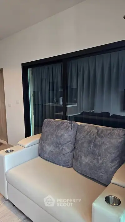 Modern living room with stylish sofa and large window, perfect for relaxation and natural light.
