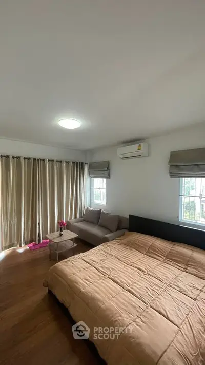 Spacious bedroom with cozy sofa and large windows for natural light