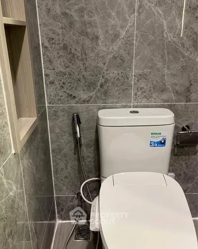 Modern bathroom with sleek marble tiles and high-tech toilet features.