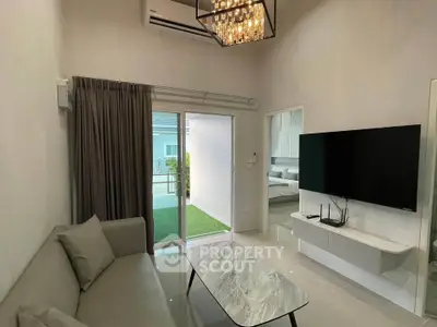 Modern living room with sleek decor and large TV, opening to a private balcony.