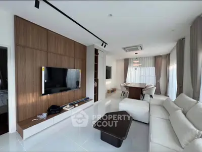 Modern living room with sleek design, featuring a large TV, elegant furniture, and ample natural light.