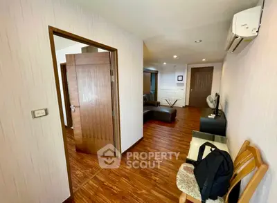 Spacious living area with wooden flooring and modern furnishings in a stylish apartment.