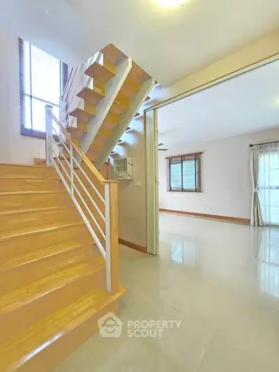 Spacious modern interior with wooden staircase and bright living area, perfect for family living.