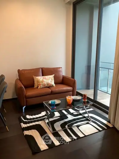 Stylish living room with modern sofa and glass coffee table near a large window.