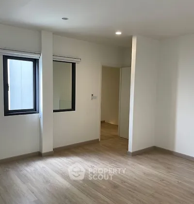 Spacious empty room with wooden flooring and large windows, ideal for customization.