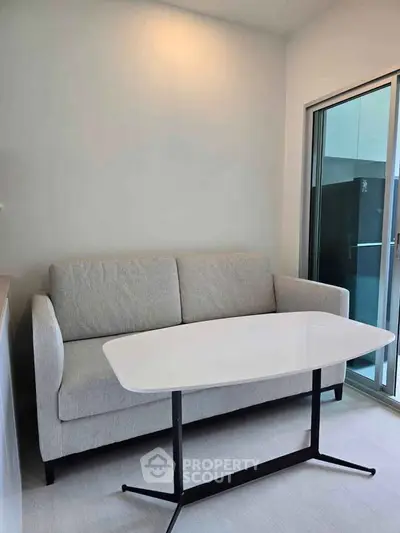 Modern living room with sleek sofa and stylish table near glass sliding doors.