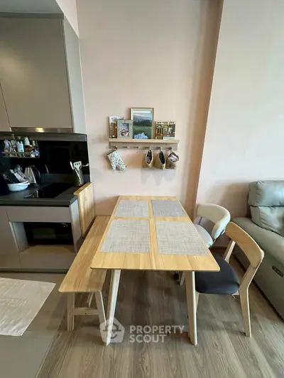 Modern kitchen with sleek appliances and cozy dining area featuring wooden table and chairs.