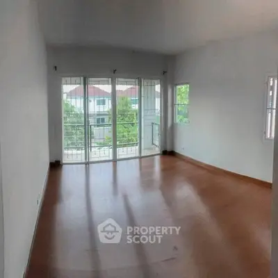 Spacious empty living room with large windows and balcony view.