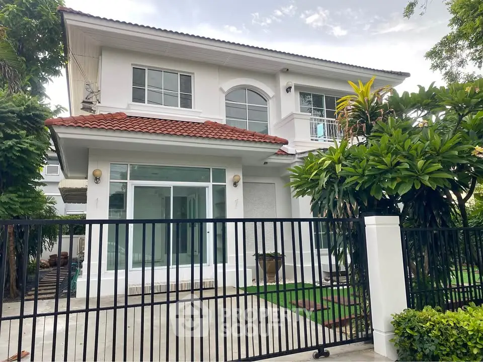 Elegant two-story house with red-tiled roof and lush greenery, perfect for family living.