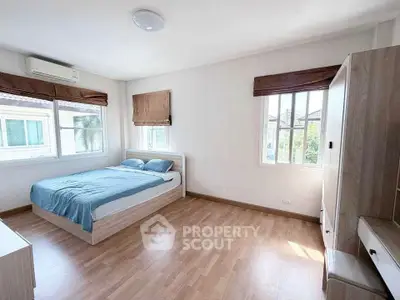 Spacious bedroom with wooden flooring and natural light
