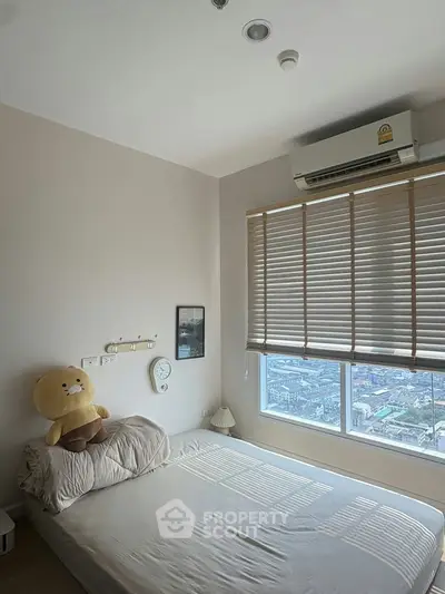 Cozy bedroom with city view, featuring a plush toy and air conditioning, perfect for relaxation.