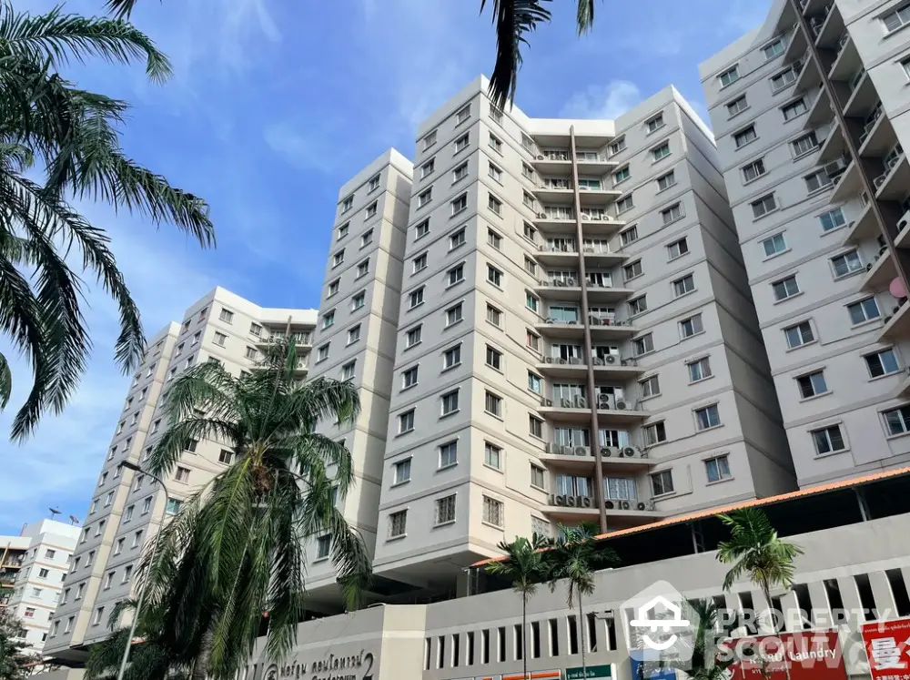 Modern high-rise apartment building with palm trees and clear blue sky