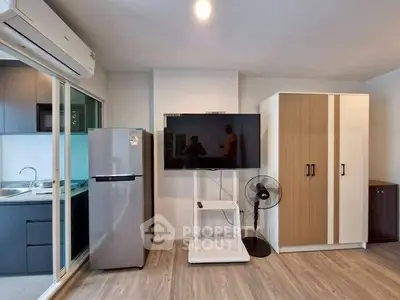 Modern living room with sleek kitchen, TV, and stylish furniture in a contemporary apartment.