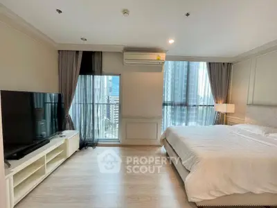 Spacious modern bedroom with large windows and city view, featuring a sleek TV setup.