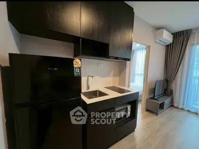 Modern kitchen with sleek black cabinets and compact appliances in a stylish apartment.