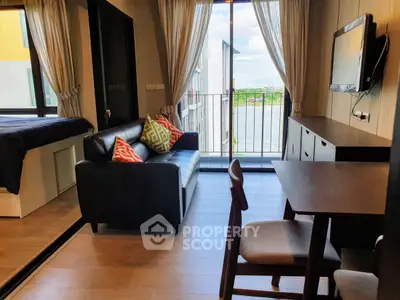 Modern living room with balcony view, stylish furniture, and natural light.