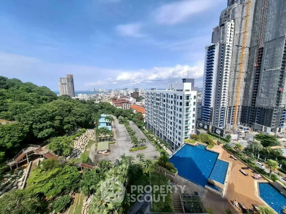 Stunning cityscape view from high-rise building with pool and lush greenery.