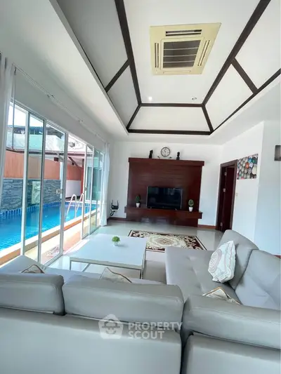 Luxurious living room with pool view, modern decor, and elegant ceiling design.