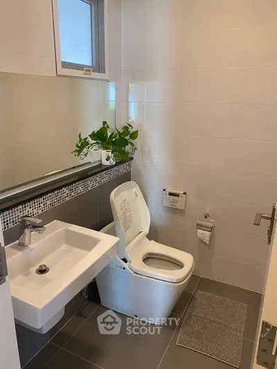 Modern bathroom with sleek fixtures and a touch of greenery for a refreshing ambiance.
