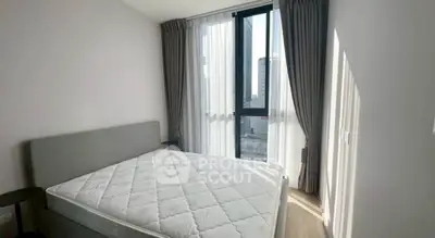 Bright bedroom with large window and modern decor in urban apartment.