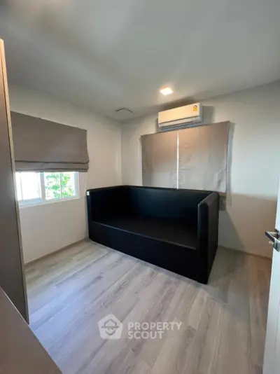 Cozy small room with modern black sofa and air conditioning, perfect for a compact living space.