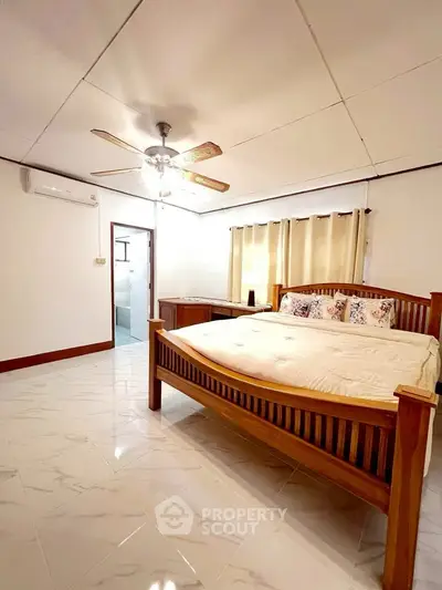 Spacious bedroom with wooden bed and ceiling fan in a bright, airy setting.