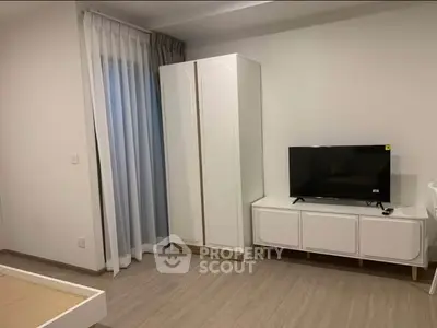 Modern bedroom with sleek wardrobe and TV unit, featuring minimalist design and natural light.